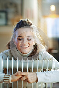 Happy modern 40 years old woman embracing warm oil radiator