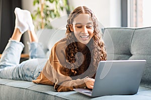 Happy modern adolescent girl enjoys e-learning with laptop at home