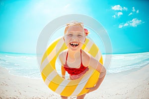 Happy modern child with yellow inflatable lifebuoy on beach