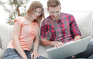 Happy modern couple surfing the net and working on laptop at home