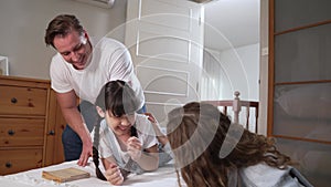 Happy modern family wakes up their little girl with tickle. Fastidious