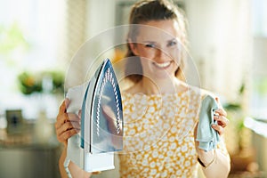 Happy modern female cleaning iron with cloth