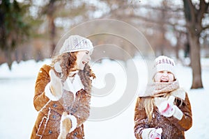 Happy modern mother and child shaking off snow from mittens