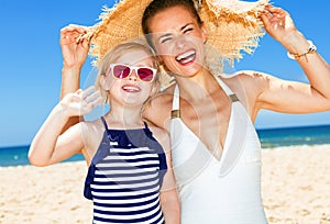 Happy modern mother and daughter on seacoast handwaving