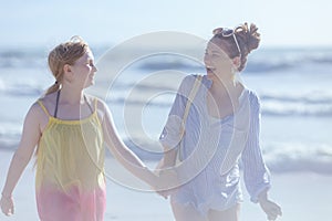 happy modern mother and teenage daughter at beach walking