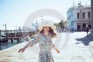 Happy modern traveller woman in floral dress sightseeing