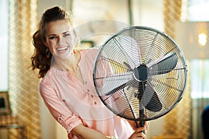 Happy modern woman near electric floor standing fan