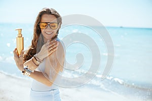 happy modern woman on seashore with sunscreen