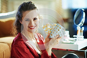Happy modern woman showing blisters with pills