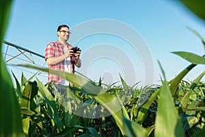 Happy modern young farmer inspecting his fields with a drone