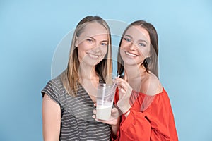 Happy mom and adult daughter drink milkshakes and laugh merrily in dresses
