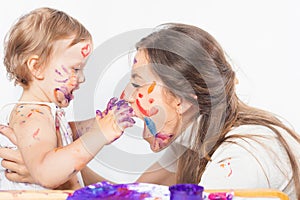 Happy mom and baby playing with painted face by paint