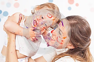 Happy mom and baby playing with painted face by paint