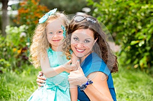 Happy mom and child girl hugging in outdoor. The concept of childhood and family. Portrait parent mother and kid. Positive human e