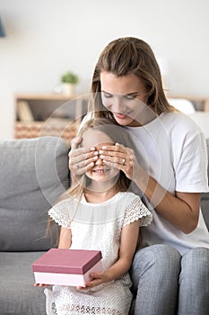 Happy mom closing daughter eyes presenting birthday gift