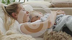 Happy mom cuddles her son child baby, lying at home between pillows, healthy and cared for growth concept