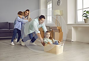 Happy mom, dad and little children playing and having fun in their new house or apartment