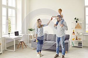 Happy mom, dad and son enjoying their weekend at home and playing fun games together