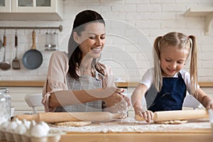 Happy mom and daughter baking pie at home together