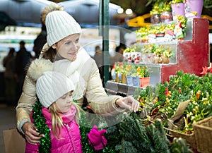 Happy mom with daughter buy spruce twigs for Christmas celebration