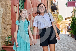 Happy mom and daughter child walking together holding hands along city street