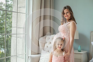 Happy mom and daughter. Pregnant woman and little child girl