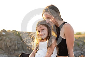 Happy mom and daughter relaxing on rocks in nature against the backdrop of the river. Happy Motherhood, Mother's Day