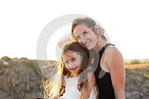 Happy mom and daughter relaxing on rocks in nature against the backdrop of the river. Happy Motherhood, Mother& x27;s Day