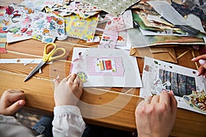 Happy mom and daughter sitting in the old style kitchen and doing scrapbooking