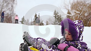 Happy mom and daughter sledding in winter in snow and playing snowballs. Mother and child laugh and rejoice glide on an