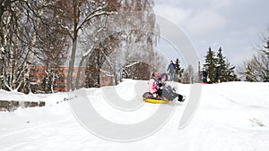 Happy mom and daughter sledding in winter in snow and playing snowballs. Mother and child laugh and rejoice glide on an