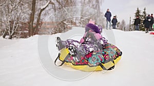 Happy mom and daughter sledding in winter in snow and playing snowballs. mother and child laugh and rejoice glide on an