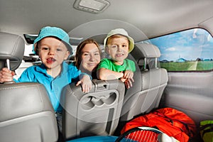 Happy mom having fun with her sons sitting in car