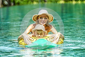 Happy mom having fun swimming with little child at luxury outdoor swimming pool. Summer vacation. Family lifestyle