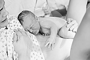 Happy mom, having her baby skin to skin first seconds after birth