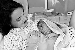 Happy mom, having her baby skin to skin first seconds after birth