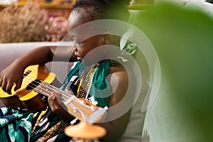 Happy Mom with her daughter playing guitar and singing together at home, happy family