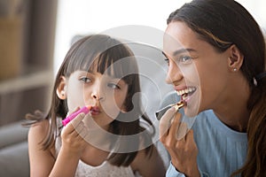 Happy mom and kid daughter having fun doing makeup together