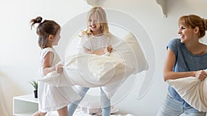 Happy mom and little daughter engaged in pillow fight