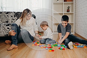 Happy mom play with sons, mother engaged with boys children. Family