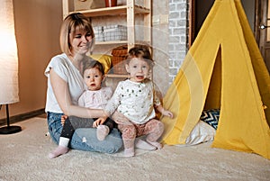 happy mom playing on the floor with two twin girls.