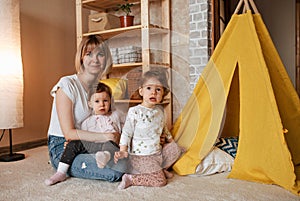 happy mom playing on the floor with two twin girls.