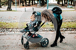 Happy mom pushing stroller and smiling, laughing. Young mother taking care of little son