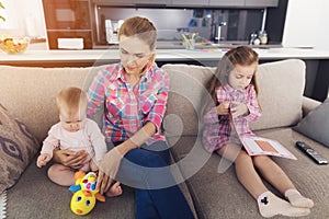 Happy Mom Sitting with Two Kids on Sofa at Home