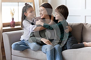 Happy mom and small kids relax on couch cuddling