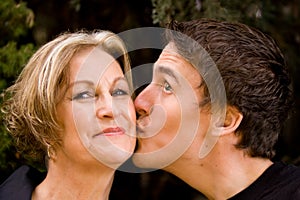 Happy mom smiling and son giving kiss