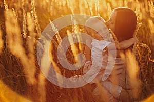 Happy mom with son in the field at sunset. happy childhood. A young woman hugs her son