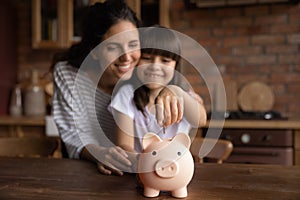 Happy mom teaching smart daughter girl to save money