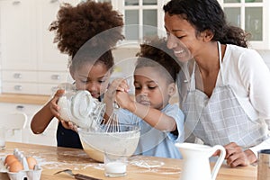 Happy mom teaching two preschooler kids to bake pie