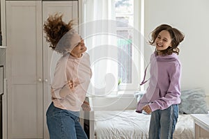 Happy mom and teen daughter dance have fun at home